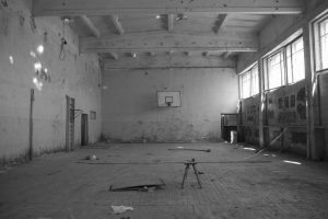 black and white photo of an interior of an abandoned school gym