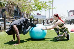 a couple exercising on green grass near the building