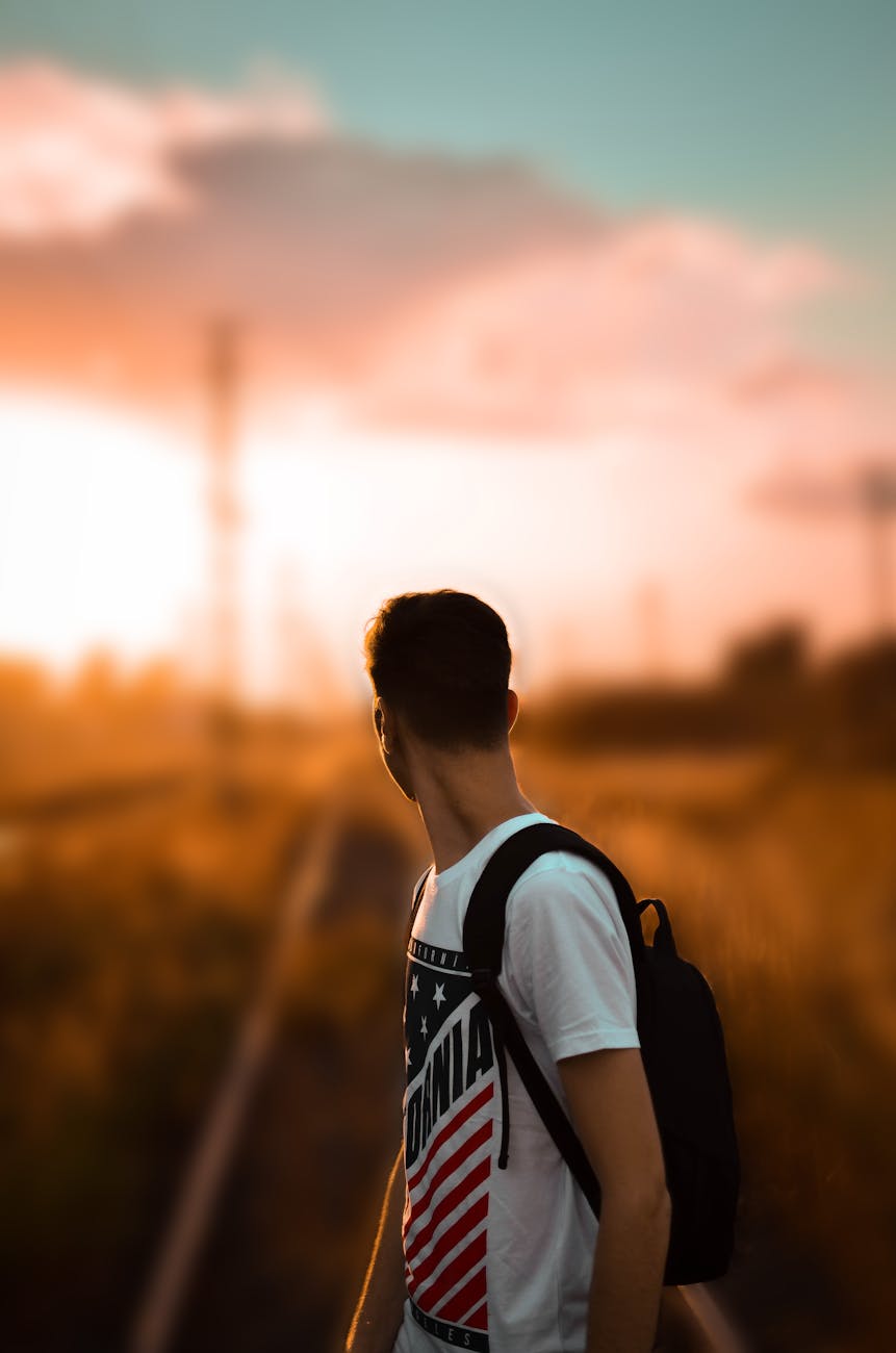 selective focus photography of a man in white printed t shirt carrying backpack